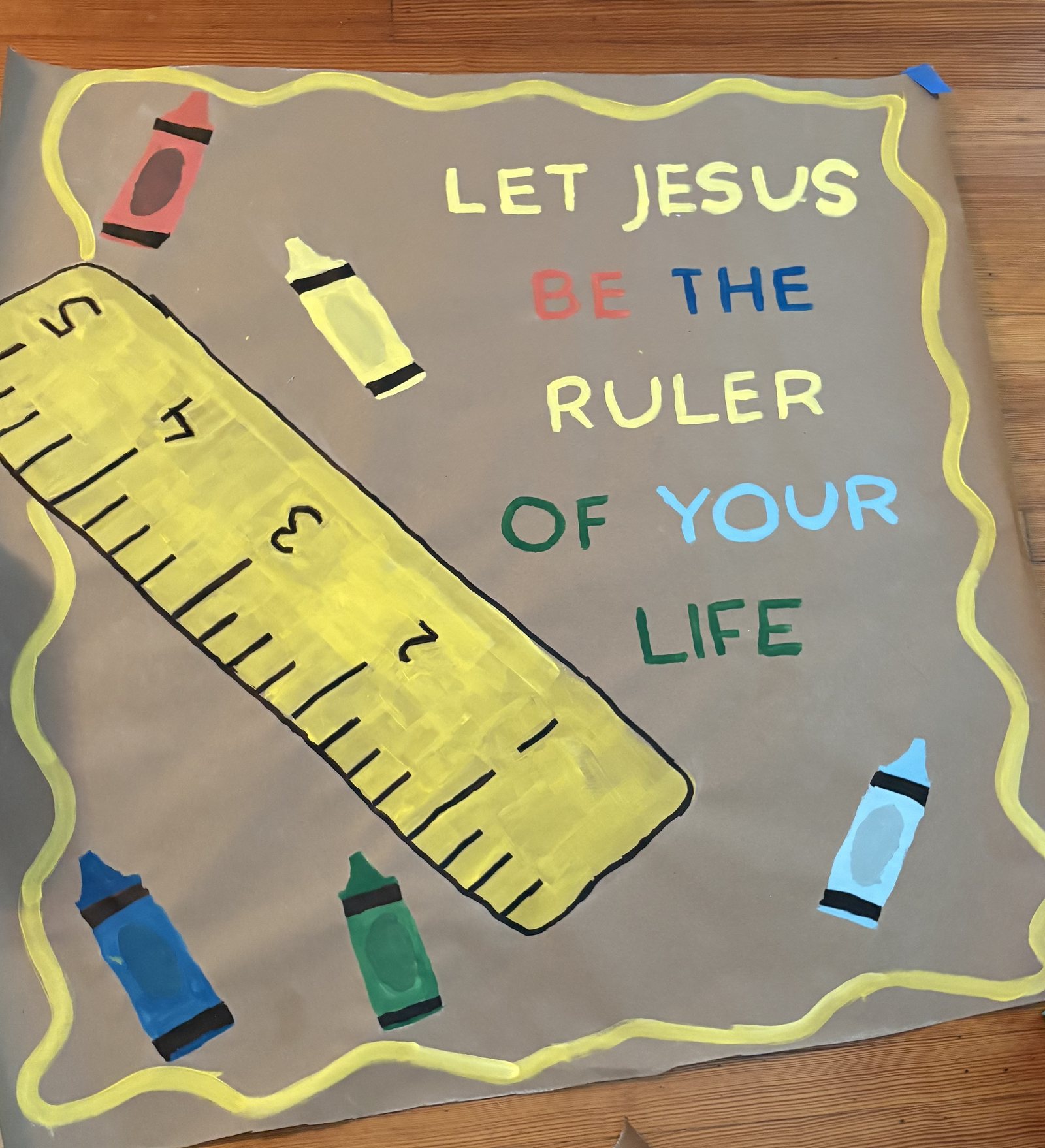 Hand-painted banner reading Let Jesus Be The Ruler Of Your Life with painted crayons, a hand-drawn yellow ruler and a wavy yellow border