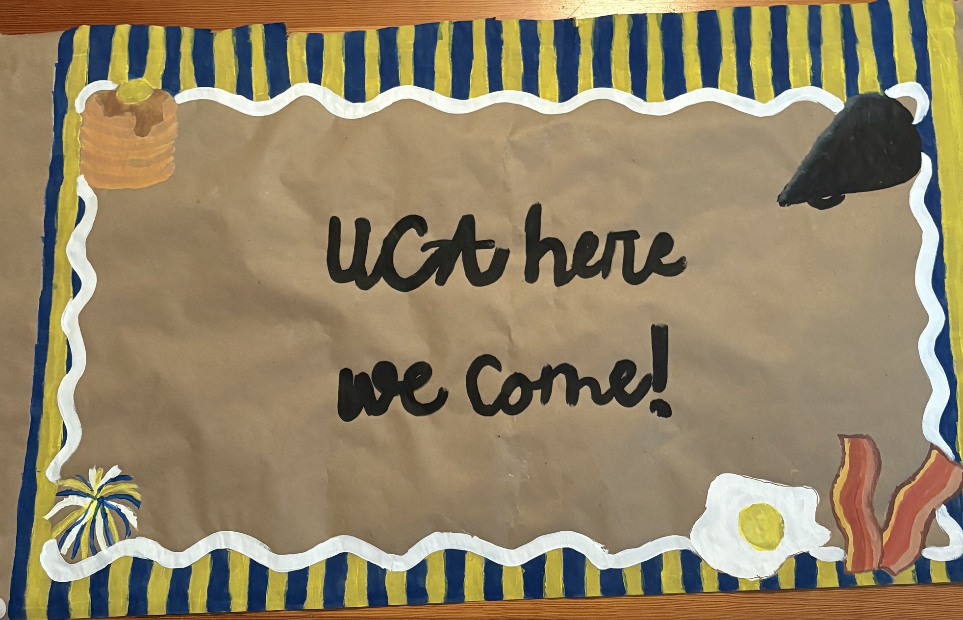 Hand-painted cheer send-off banner reading UCA here we come